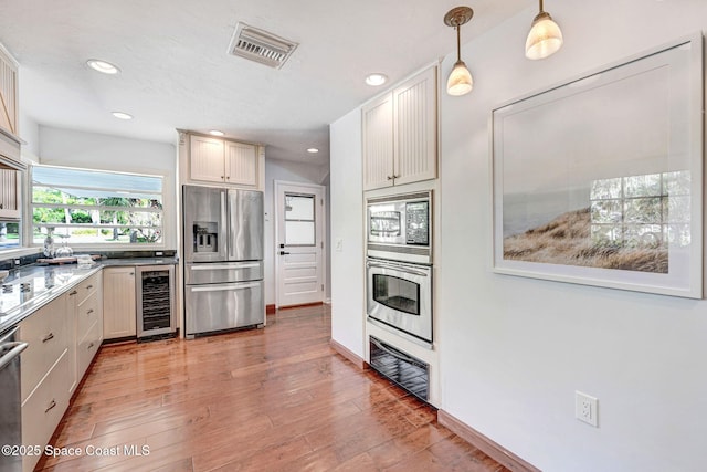 kitchen featuring visible vents, wine cooler, light wood-style floors, and appliances with stainless steel finishes