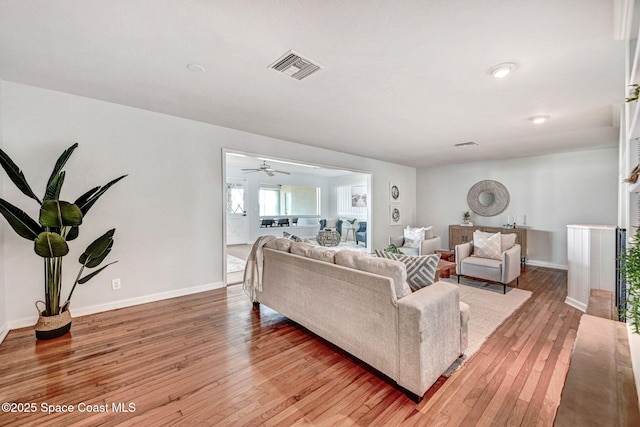 living area featuring visible vents, baseboards, light wood-style floors, and a ceiling fan