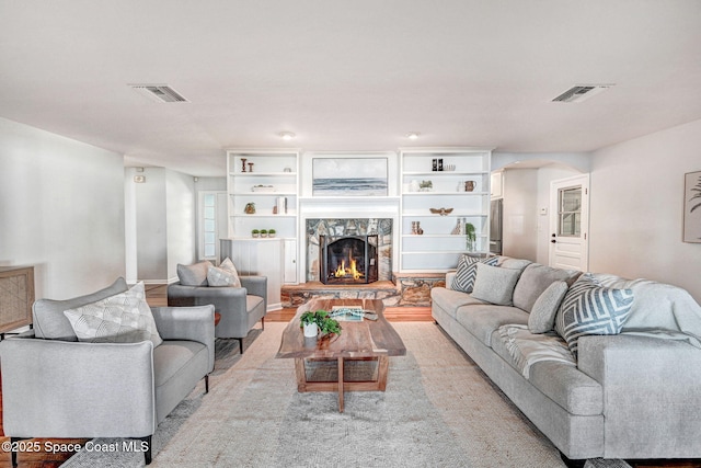 living room featuring light wood finished floors, visible vents, and a fireplace