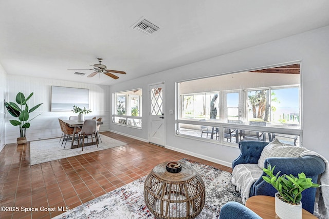 tiled living room with a ceiling fan, visible vents, and baseboards