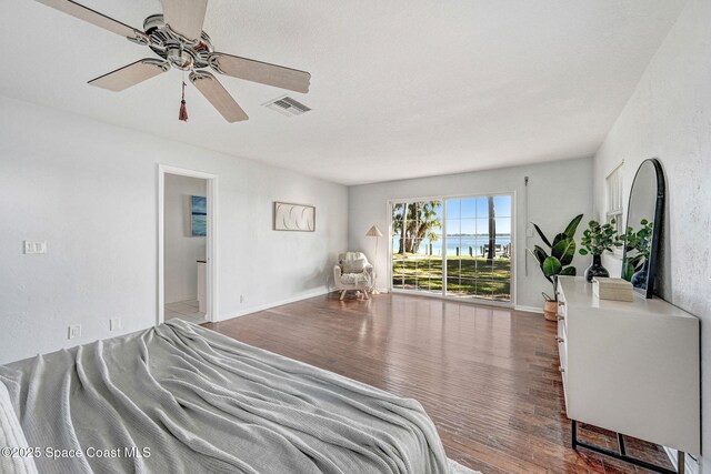 bedroom with a ceiling fan, wood finished floors, visible vents, and baseboards