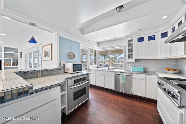 kitchen featuring white cabinets, hanging light fixtures, dark hardwood / wood-style floors, backsplash, and appliances with stainless steel finishes