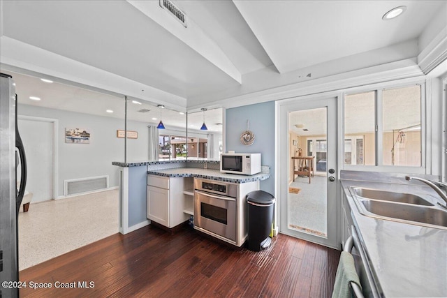 kitchen with white cabinetry, sink, appliances with stainless steel finishes, dark wood-type flooring, and pendant lighting