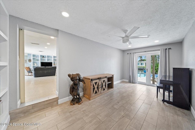 interior space with light wood-type flooring, a textured ceiling, ceiling fan, and french doors