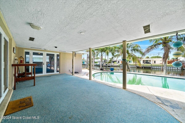 view of pool with a water view, french doors, and a patio area