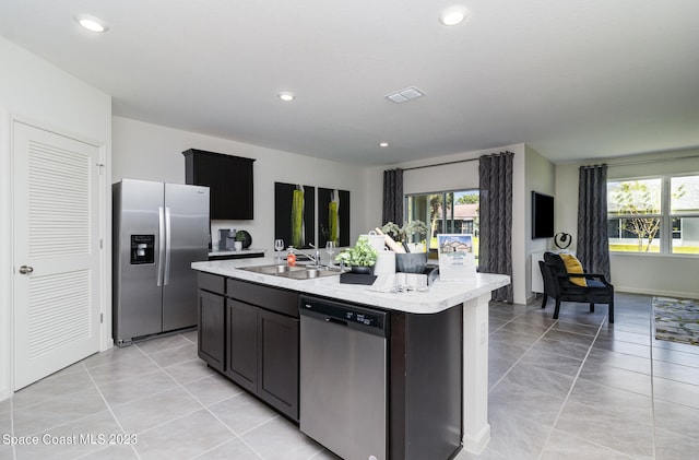 kitchen with a wealth of natural light, appliances with stainless steel finishes, sink, and a kitchen island with sink