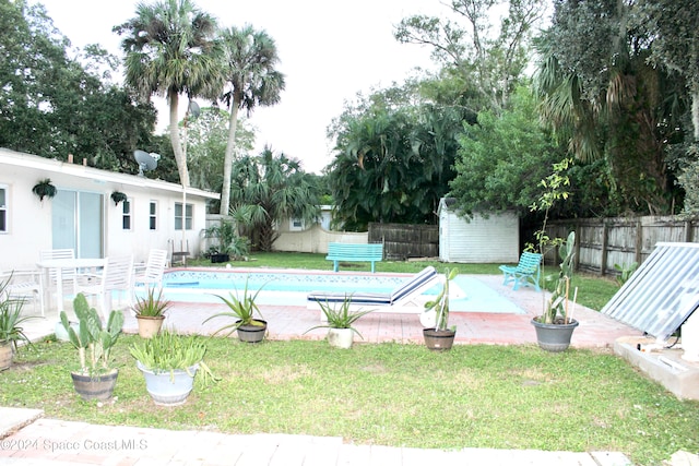 view of swimming pool featuring an outbuilding, a patio, and a yard