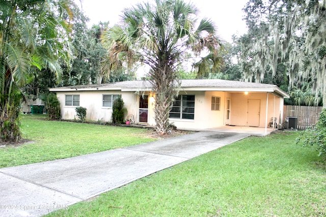 ranch-style house featuring central AC, a carport, and a front lawn