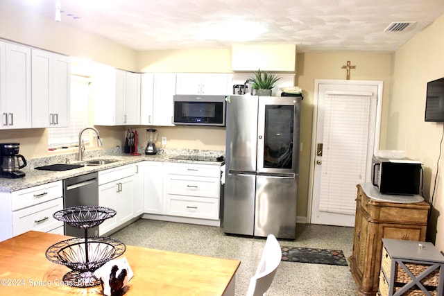 kitchen featuring white cabinets, stainless steel appliances, sink, and light stone countertops