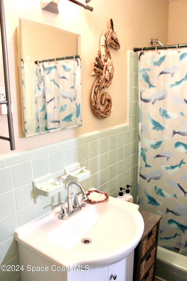 bathroom featuring tile walls, curtained shower, and vanity