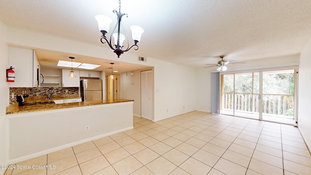 kitchen featuring kitchen peninsula, stainless steel fridge, stove, decorative backsplash, and pendant lighting