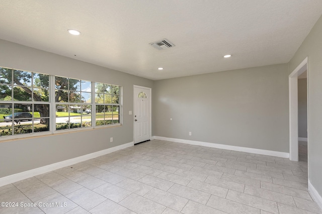 empty room featuring light tile patterned flooring and a textured ceiling
