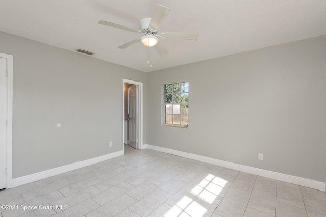 spare room featuring a textured ceiling, ceiling fan, and light tile patterned flooring