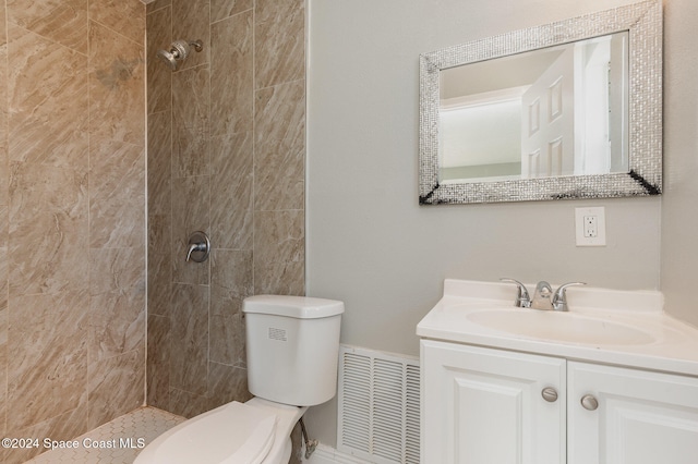 bathroom with toilet, vanity, and tiled shower