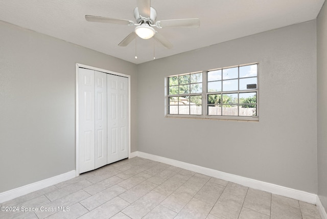 unfurnished bedroom with a closet, light tile patterned floors, and ceiling fan
