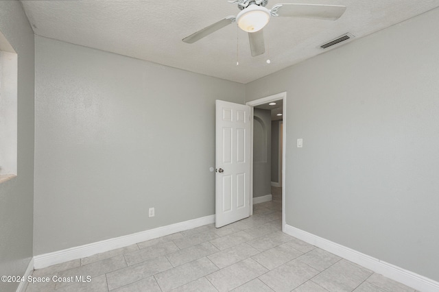 tiled spare room with ceiling fan and a textured ceiling