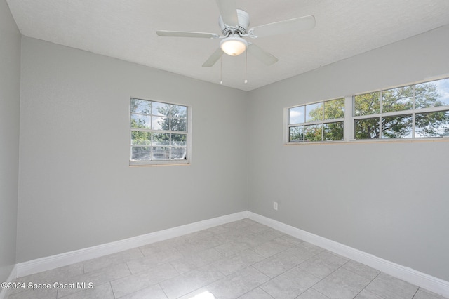 spare room with light tile patterned flooring, ceiling fan, and a textured ceiling