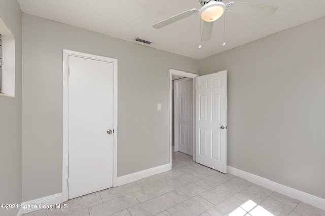 unfurnished bedroom featuring ceiling fan, light tile patterned floors, and a closet