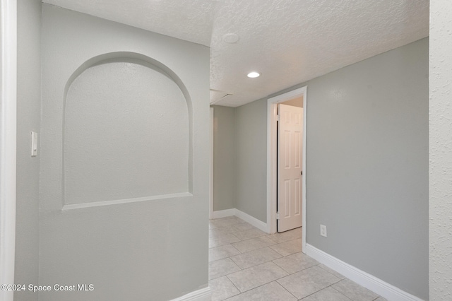corridor with a textured ceiling and light tile patterned floors