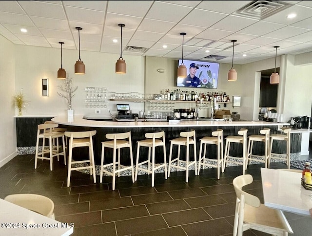 bar featuring a drop ceiling and hanging light fixtures