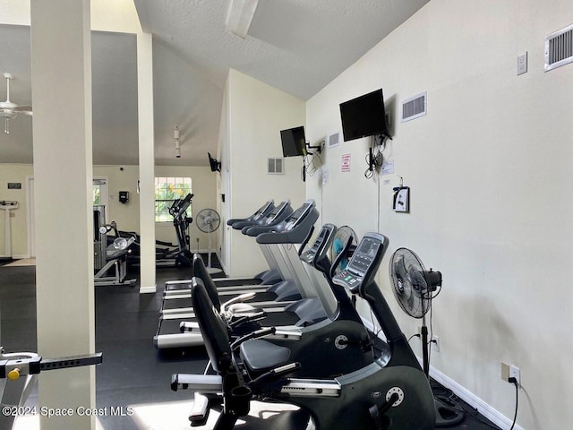 gym featuring ceiling fan, a textured ceiling, and vaulted ceiling