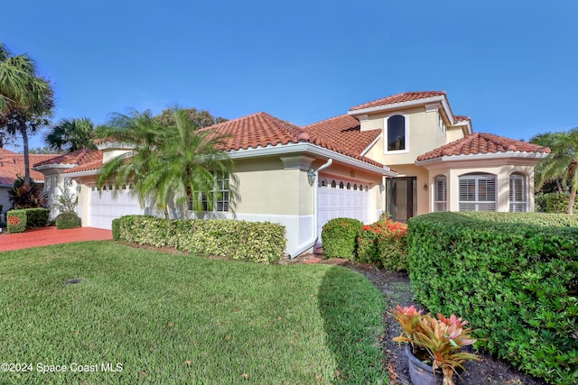 mediterranean / spanish home featuring a garage and a front lawn