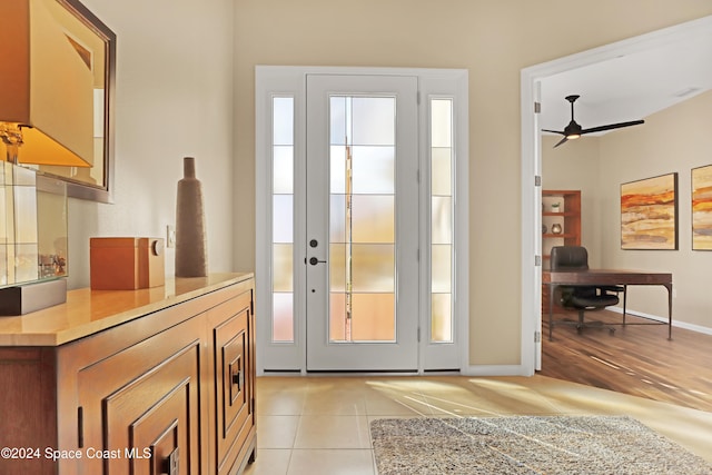 doorway to outside with ceiling fan and light tile patterned flooring