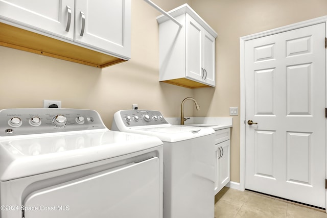 laundry area featuring washing machine and clothes dryer, cabinets, light tile patterned floors, and sink