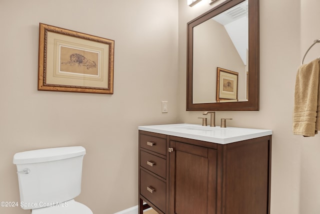 bathroom with toilet, vanity, and lofted ceiling