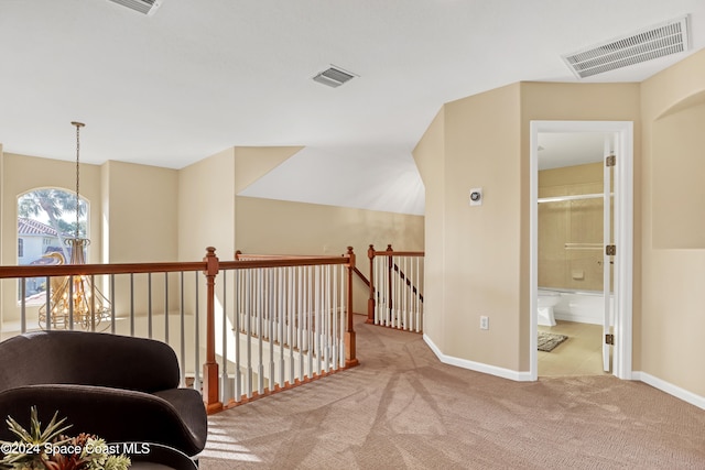 hall with light colored carpet and a chandelier