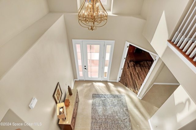 tiled foyer featuring a notable chandelier and a towering ceiling