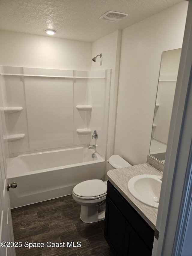 full bathroom with bathing tub / shower combination, vanity, a textured ceiling, and toilet