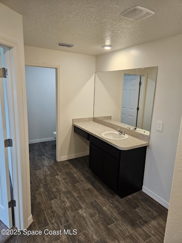 bathroom with vanity, a textured ceiling, and toilet