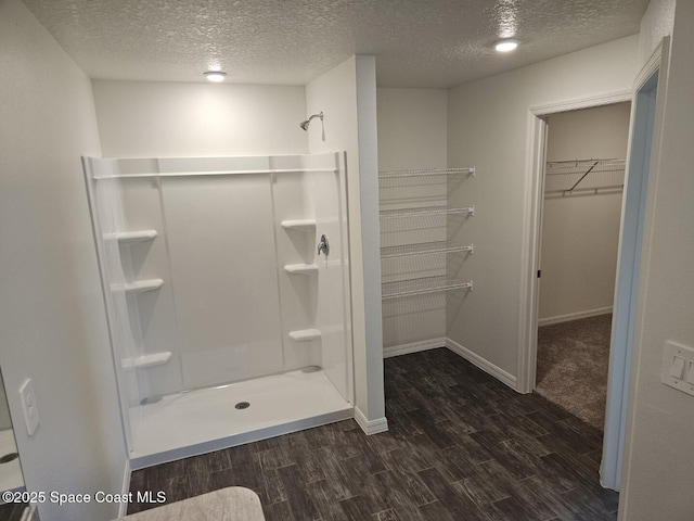 bathroom featuring a shower, hardwood / wood-style floors, and a textured ceiling