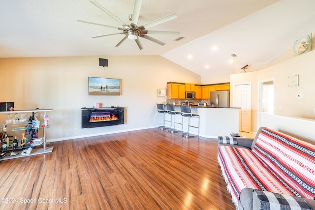 living room with lofted ceiling, dark hardwood / wood-style floors, and ceiling fan