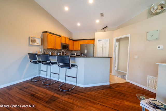 kitchen featuring kitchen peninsula, stainless steel appliances, lofted ceiling, and light hardwood / wood-style floors