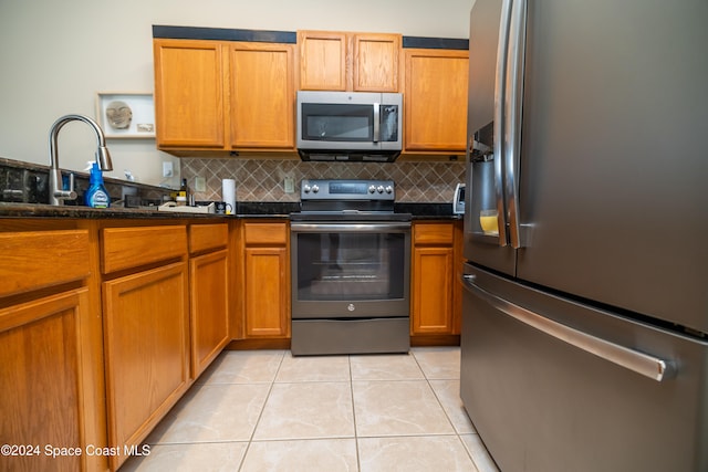 kitchen with sink, light tile patterned floors, appliances with stainless steel finishes, and tasteful backsplash