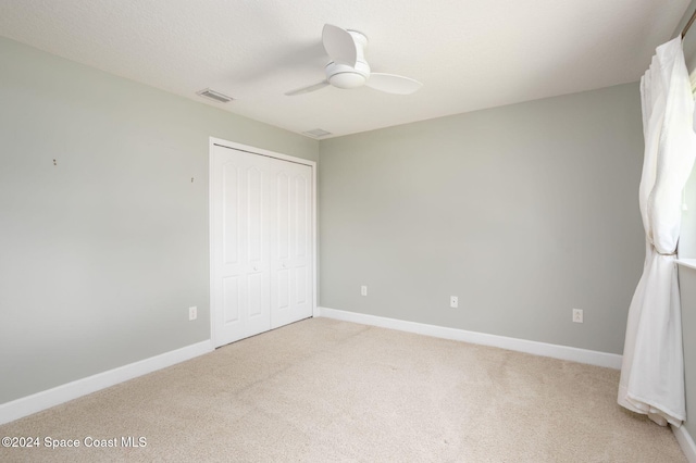 unfurnished bedroom with light carpet, ceiling fan, and a closet