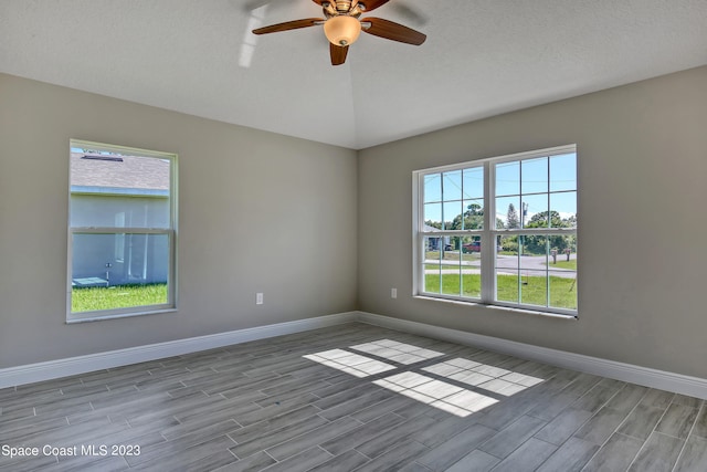 spare room with a textured ceiling, light hardwood / wood-style flooring, a healthy amount of sunlight, and ceiling fan