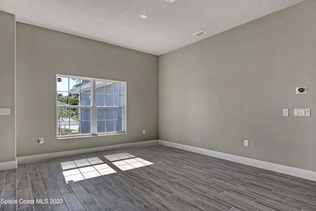 unfurnished room with wood-type flooring and a textured ceiling