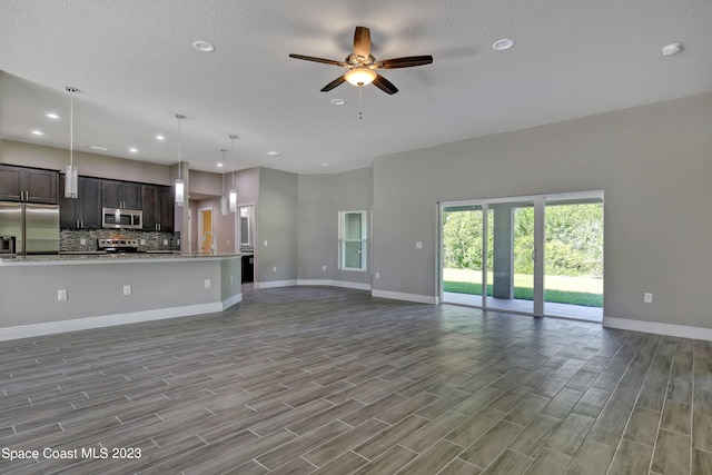 unfurnished living room with a textured ceiling, ceiling fan, and light hardwood / wood-style flooring