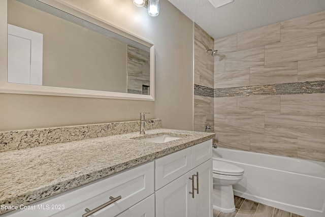 full bathroom featuring vanity, a textured ceiling, tiled shower / bath combo, hardwood / wood-style floors, and toilet