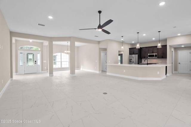 unfurnished living room with sink and ceiling fan with notable chandelier