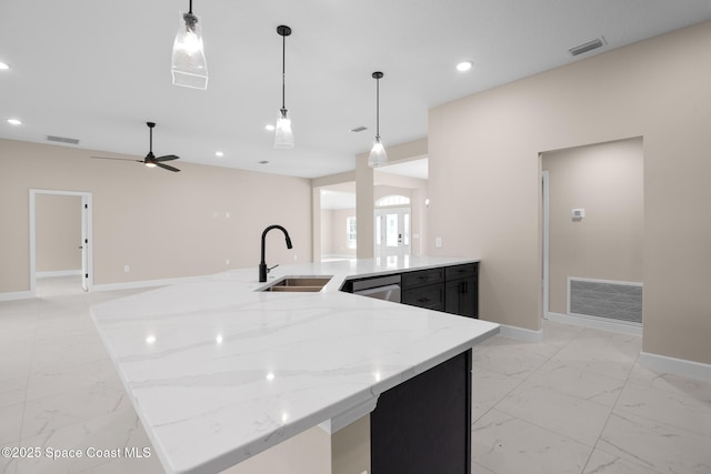 kitchen with light stone countertops, sink, stainless steel dishwasher, and decorative light fixtures