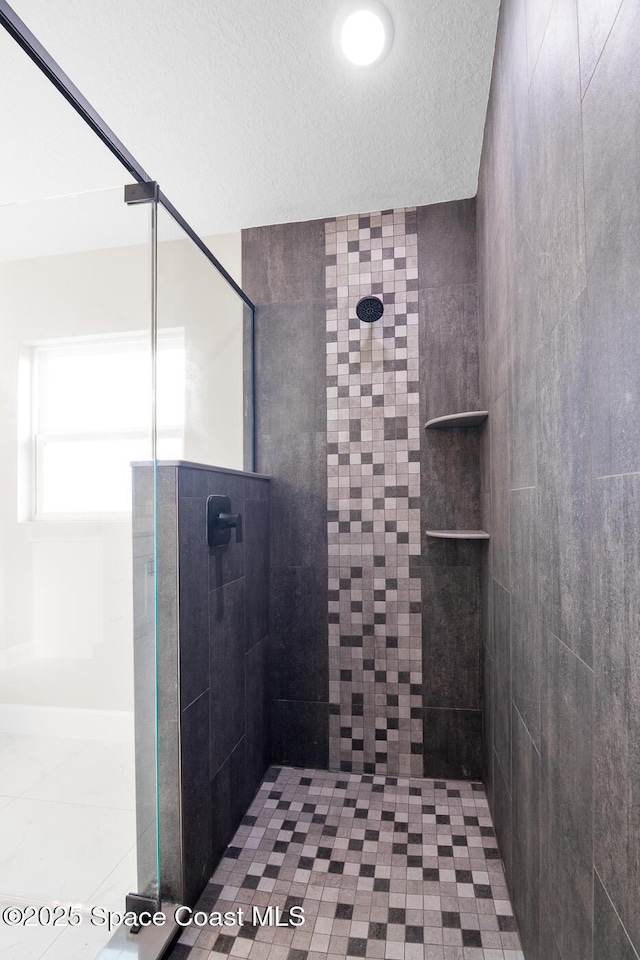 bathroom featuring a tile shower and a textured ceiling