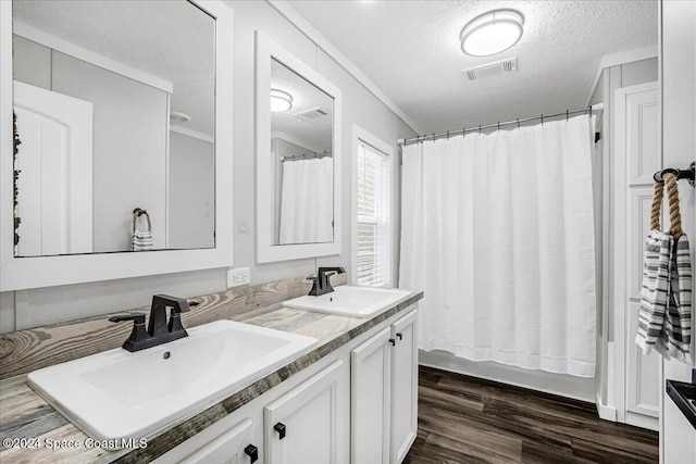 bathroom with shower / tub combo, a textured ceiling, hardwood / wood-style floors, vanity, and crown molding