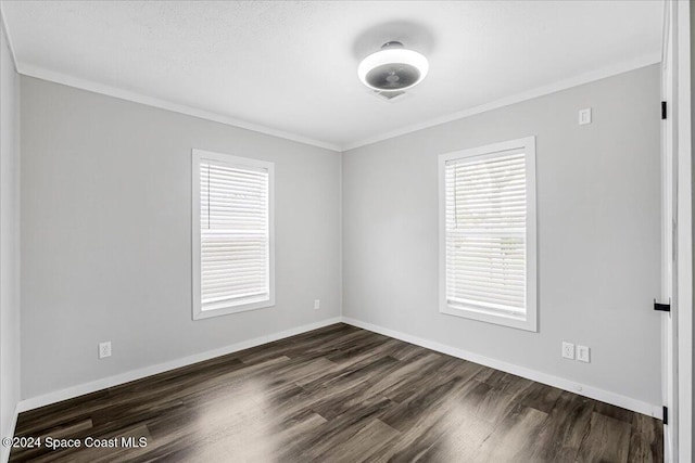 empty room featuring plenty of natural light, a textured ceiling, crown molding, and dark hardwood / wood-style flooring