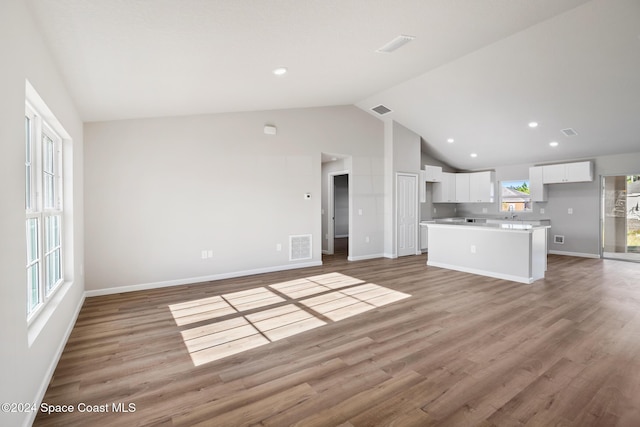 unfurnished living room featuring lofted ceiling, light hardwood / wood-style flooring, and plenty of natural light