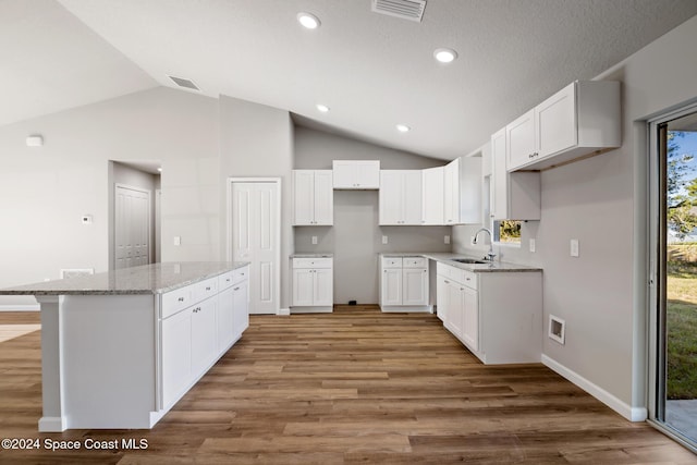 kitchen featuring dark hardwood / wood-style flooring, a center island, white cabinetry, and vaulted ceiling