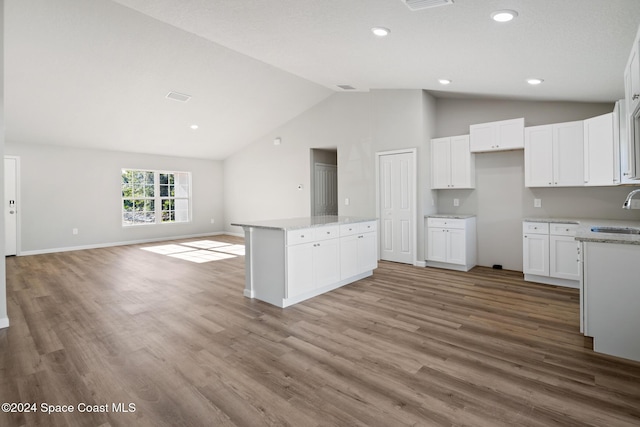 kitchen with a center island, sink, light stone countertops, light wood-type flooring, and white cabinetry